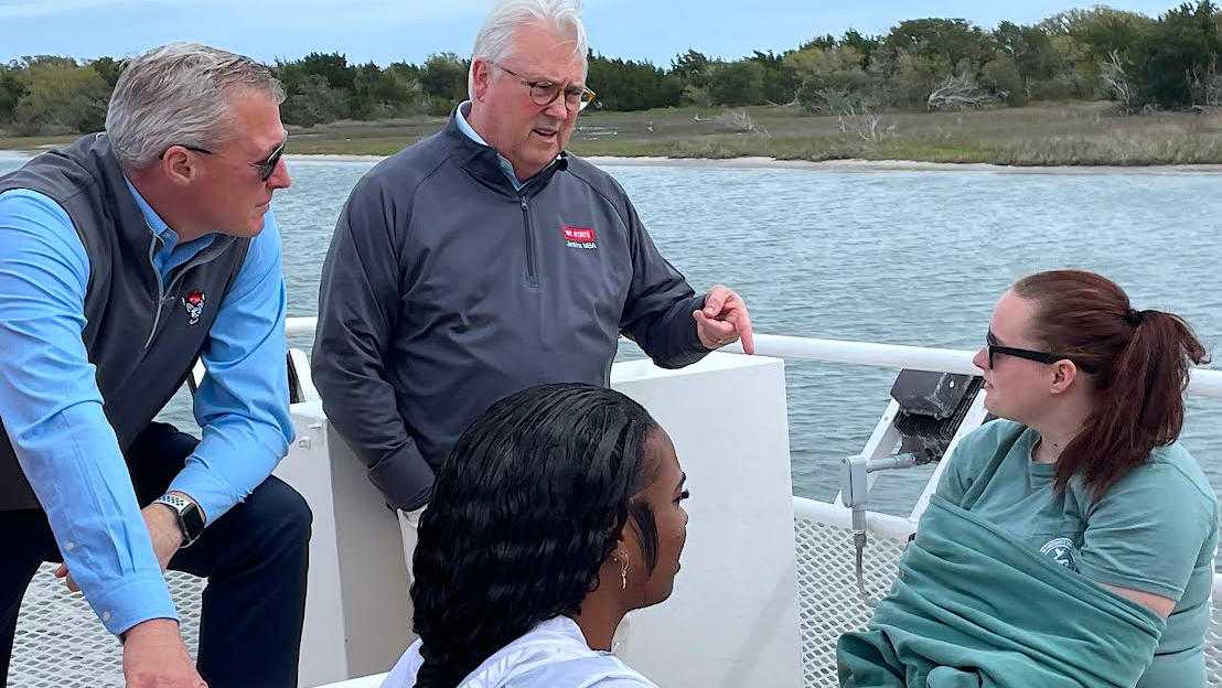 Brian Sischo, Vice Chancellor for University Advancement (left), and Chancellor Woodson (back center), talk to students during the boat tour.
